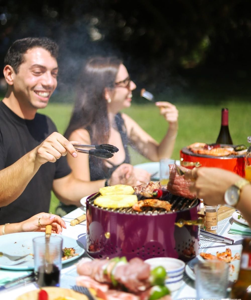 Groupe d'amis riant autour d'une grillade en plein air