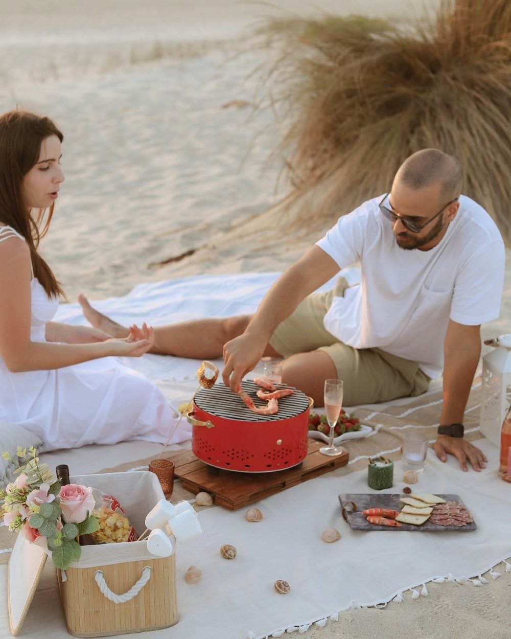 Couple sur la plage faisant griller des crevettes