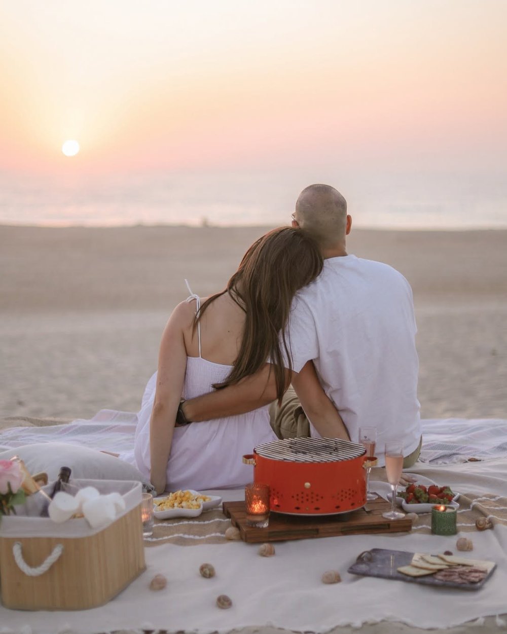 Couple regardant le coucher de soleil sur la plage devant une grille ronde